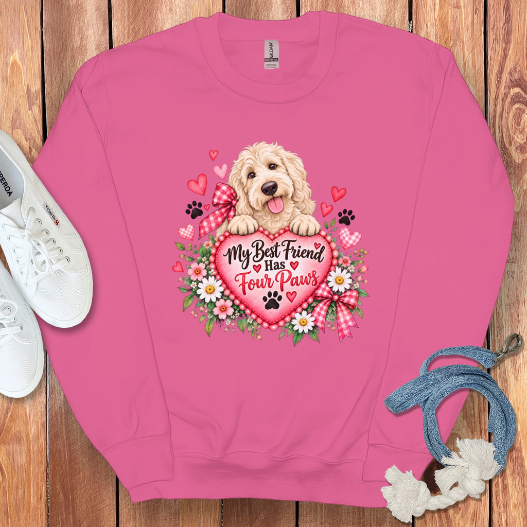 A pink sweatshirt featuring a fluffy golden dog behind a heart with the text My Best Friend Has Four Paws, surrounded by flowers and hearts.