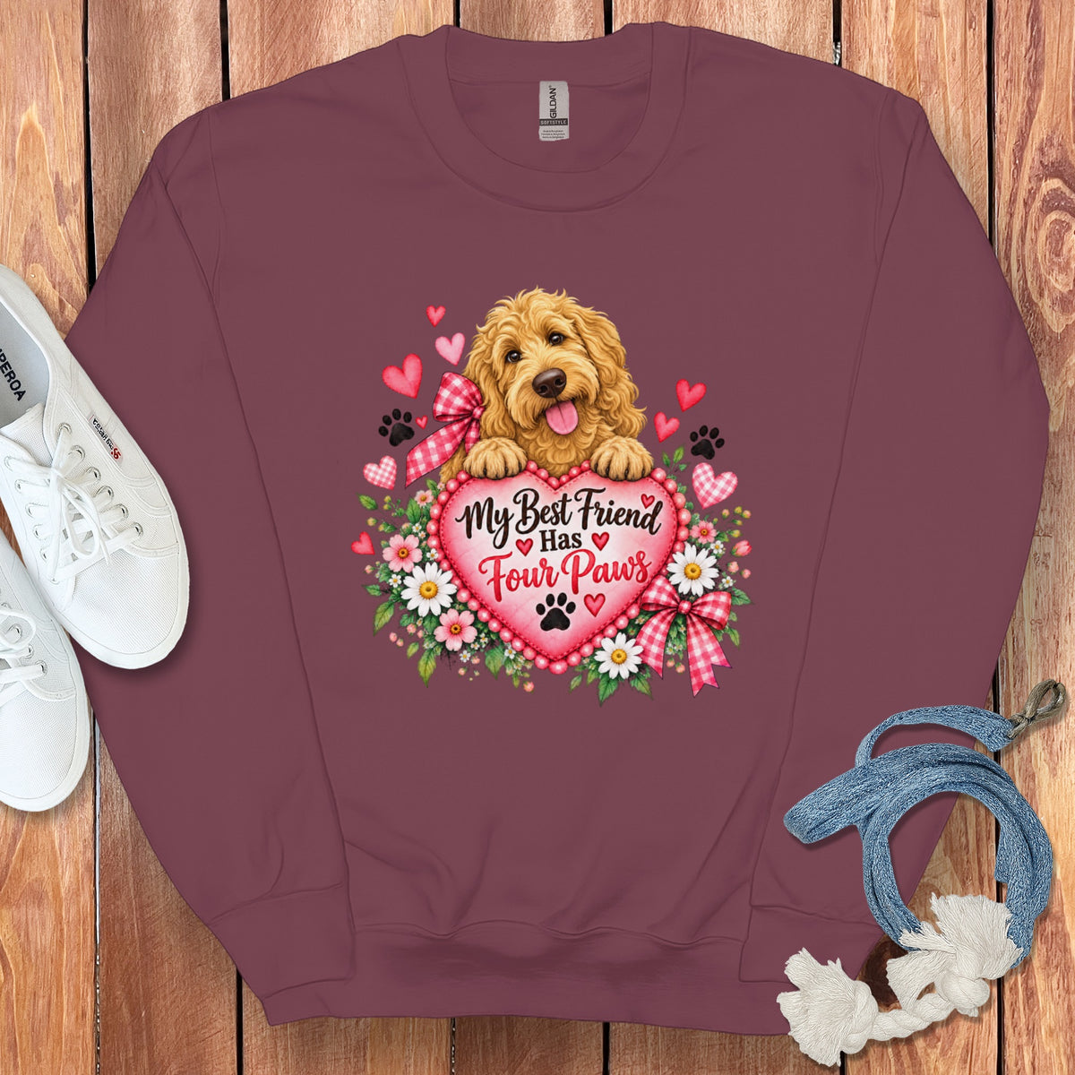 Maroon crewneck sweatshirt featuring a graphic of a golden doodle resting on a heart with the text My Best Friend Has Four Paws surrounded by flowers and hearts.