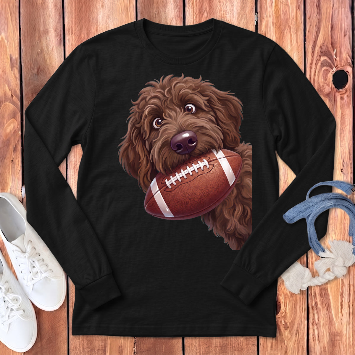 Brown doodle dog with eyes wide, holding a football in its mouth.