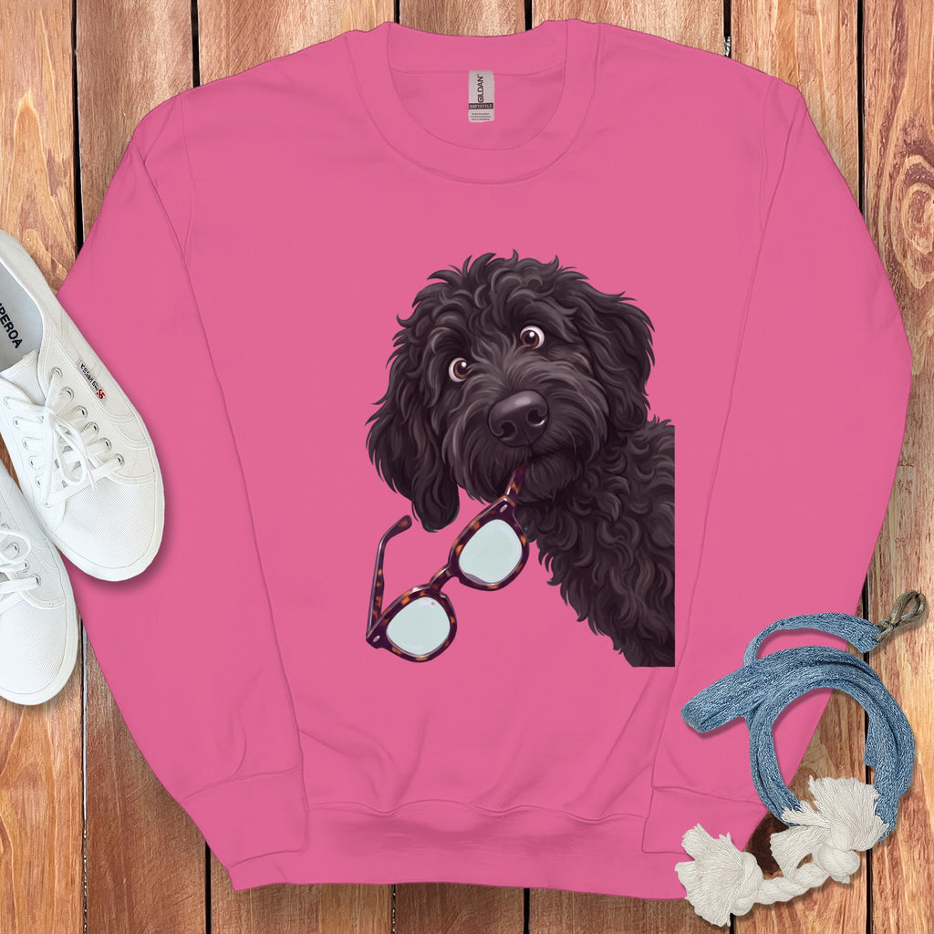 Pink crewneck sweatshirt featuring a graphic of a black doodle dog holding tortoiseshell glasses.
