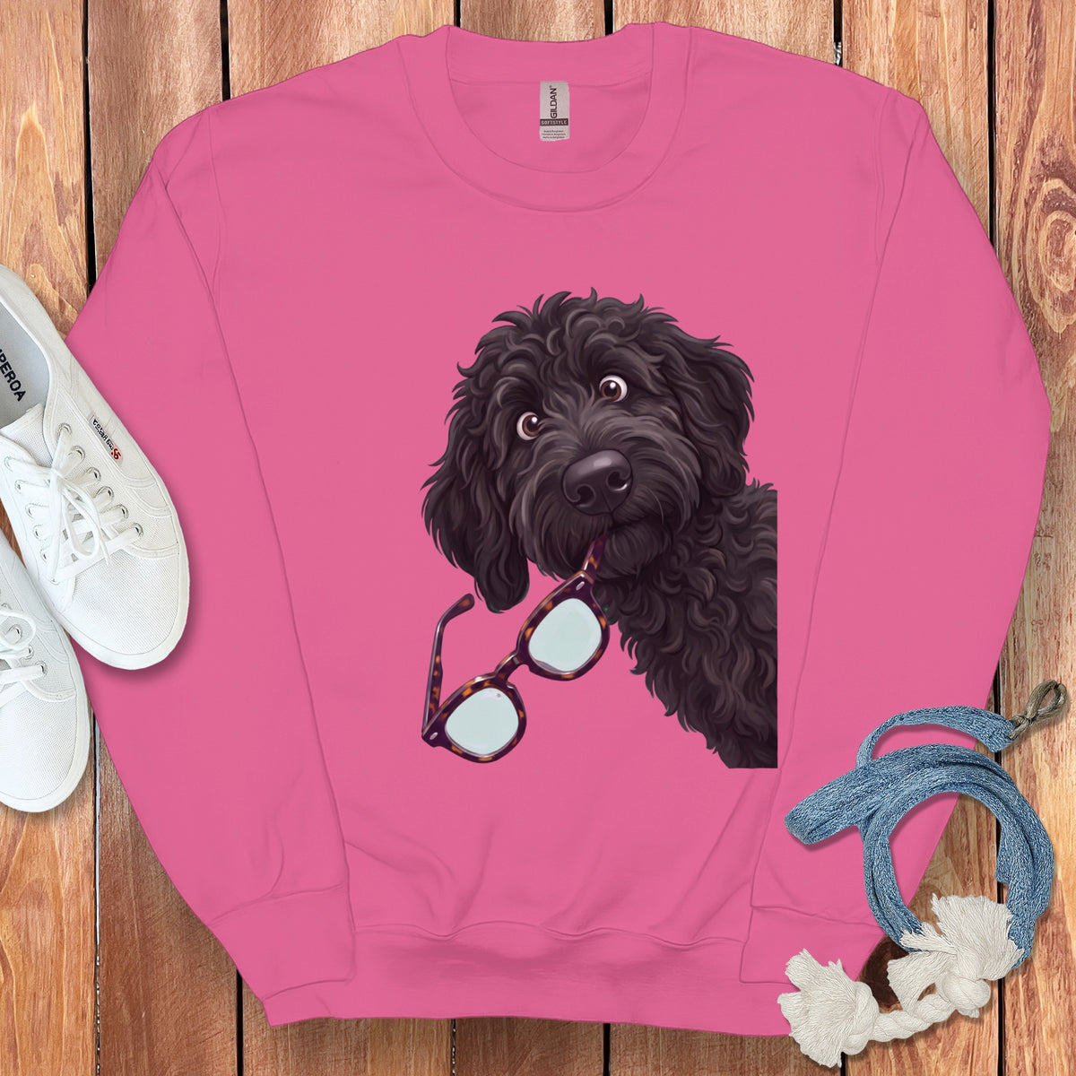 Pink crewneck sweatshirt featuring a graphic of a black doodle dog holding tortoiseshell glasses.