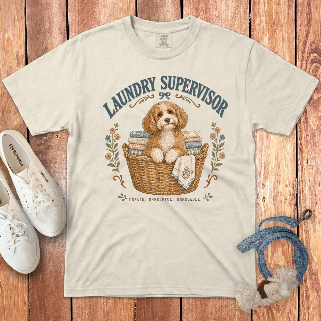 An off-white t-shirt featuring a graphic of a fluffy dog in a laundry basket with text.