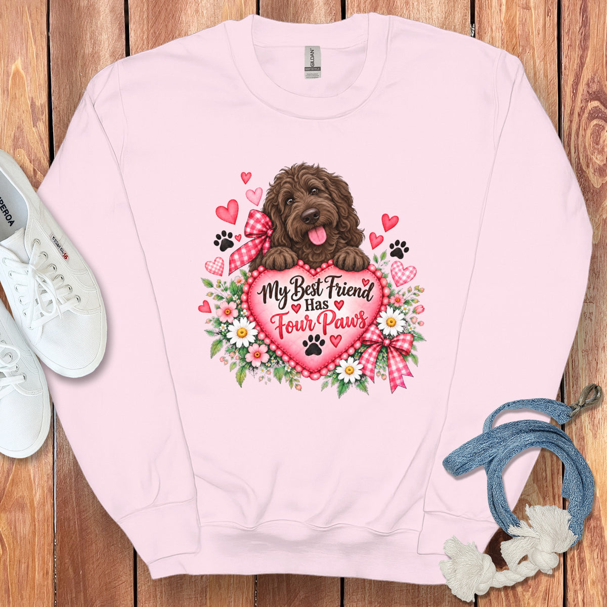 Light pink crewneck sweatshirt with a graphic of a brown dog, flowers, hearts, and the text "My Best Friend Has Four Paws".