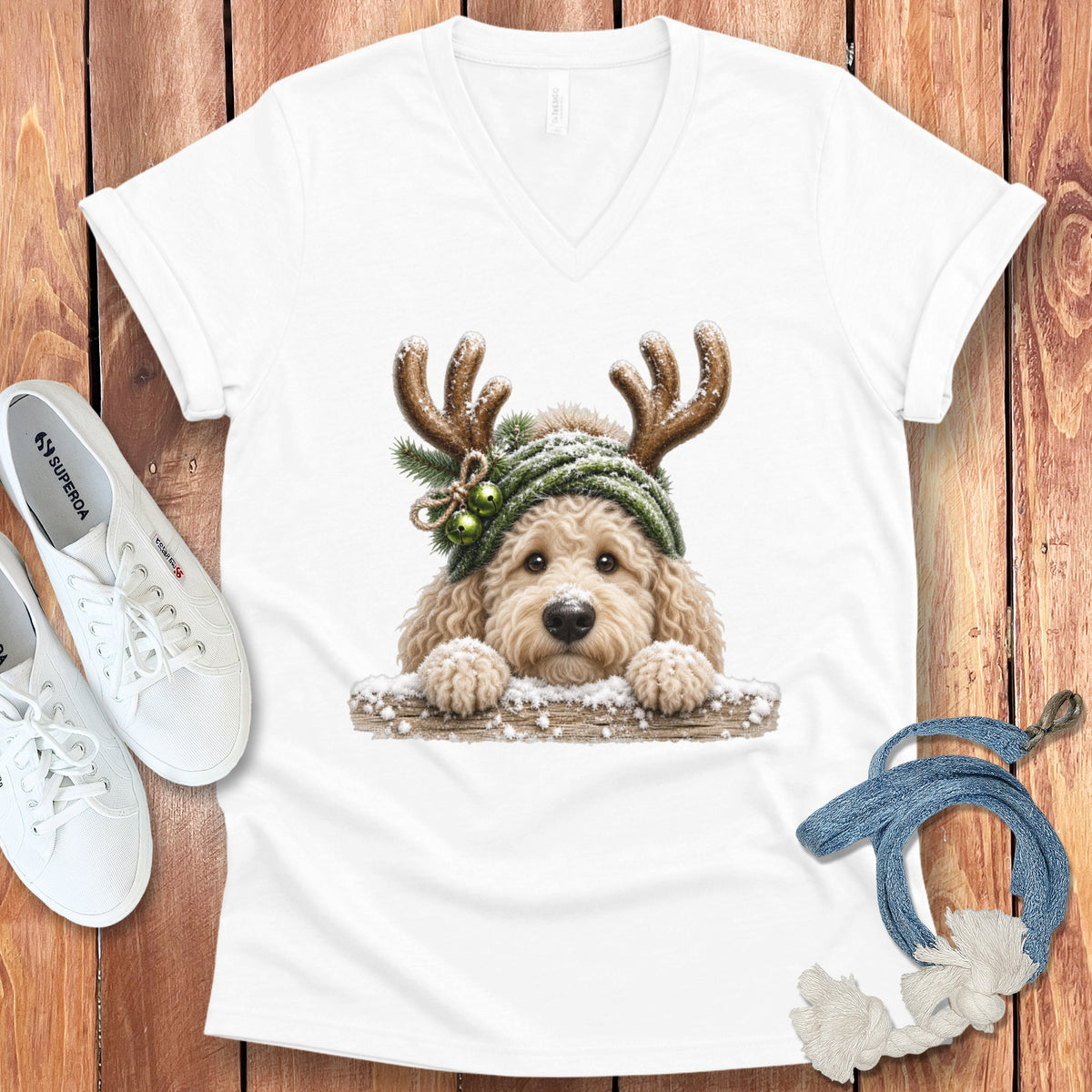 White t-shirt with a cute doodle dog wearing reindeer antlers and a green hat.