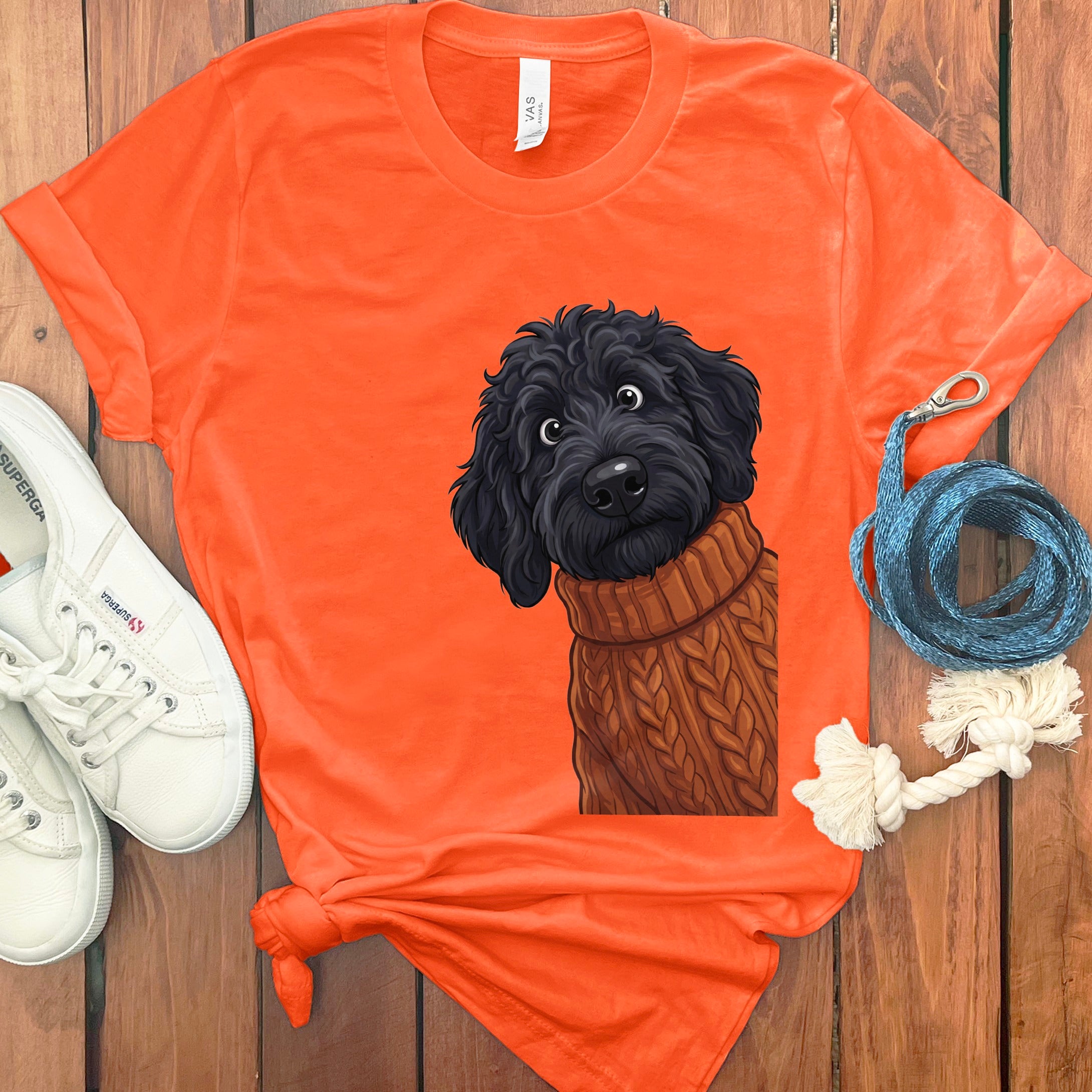 Orange t-shirt with a black doodle dog wearing a knitted sweater graphic.