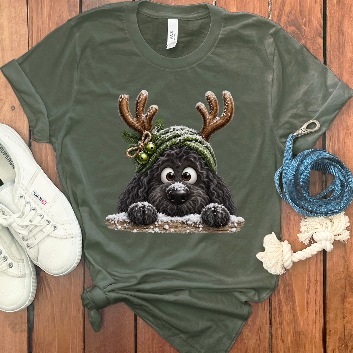 Green t-shirt with cartoon black dog wearing reindeer antlers and a hat with bells.