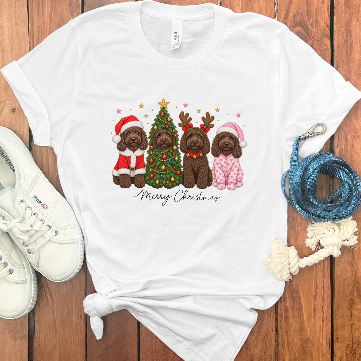 White t-shirt featuring a Christmas graphic of four brown dogs, a decorated tree, and Merry Christmas text.