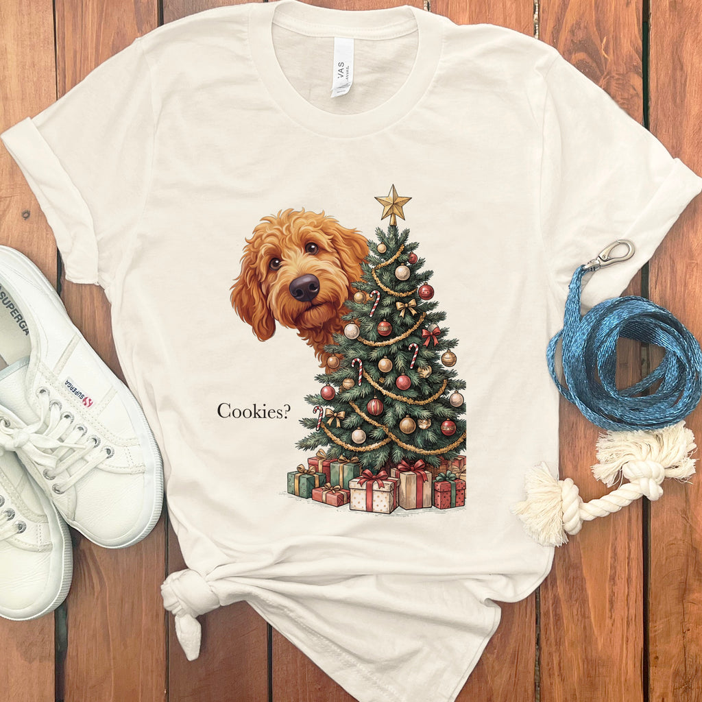 Light cream t-shirt with a doodle dog peeking around a Christmas tree, asking "Cookies?"