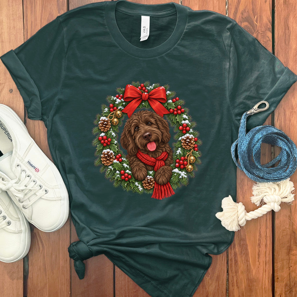 Dark green crewneck t-shirt featuring a brown dog inside a decorated Christmas wreath, with sneakers and a leash on wood.