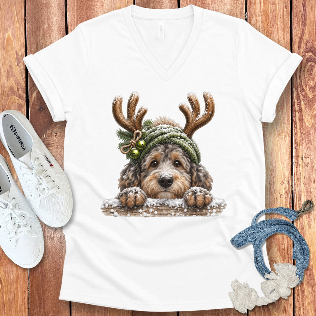 White v-neck t-shirt with a drawing of a dog wearing reindeer antlers and a green hat.