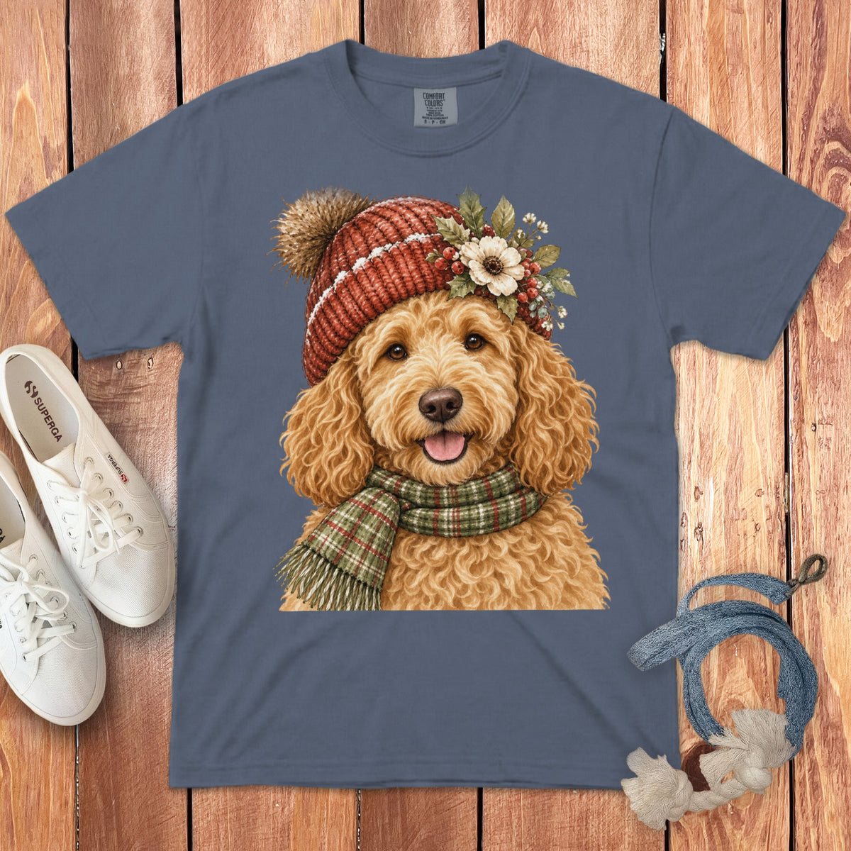 Goldendoodle wearing red beanie and green plaid scarf, printed on blue t-shirt.