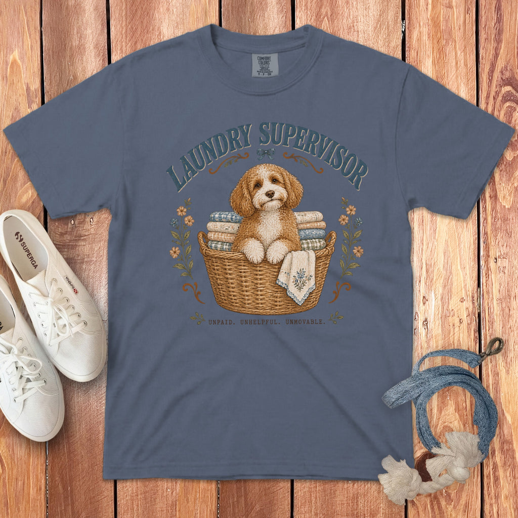 A blue crewneck t-shirt featuring a graphic of a fluffy dog in a laundry basket with text.