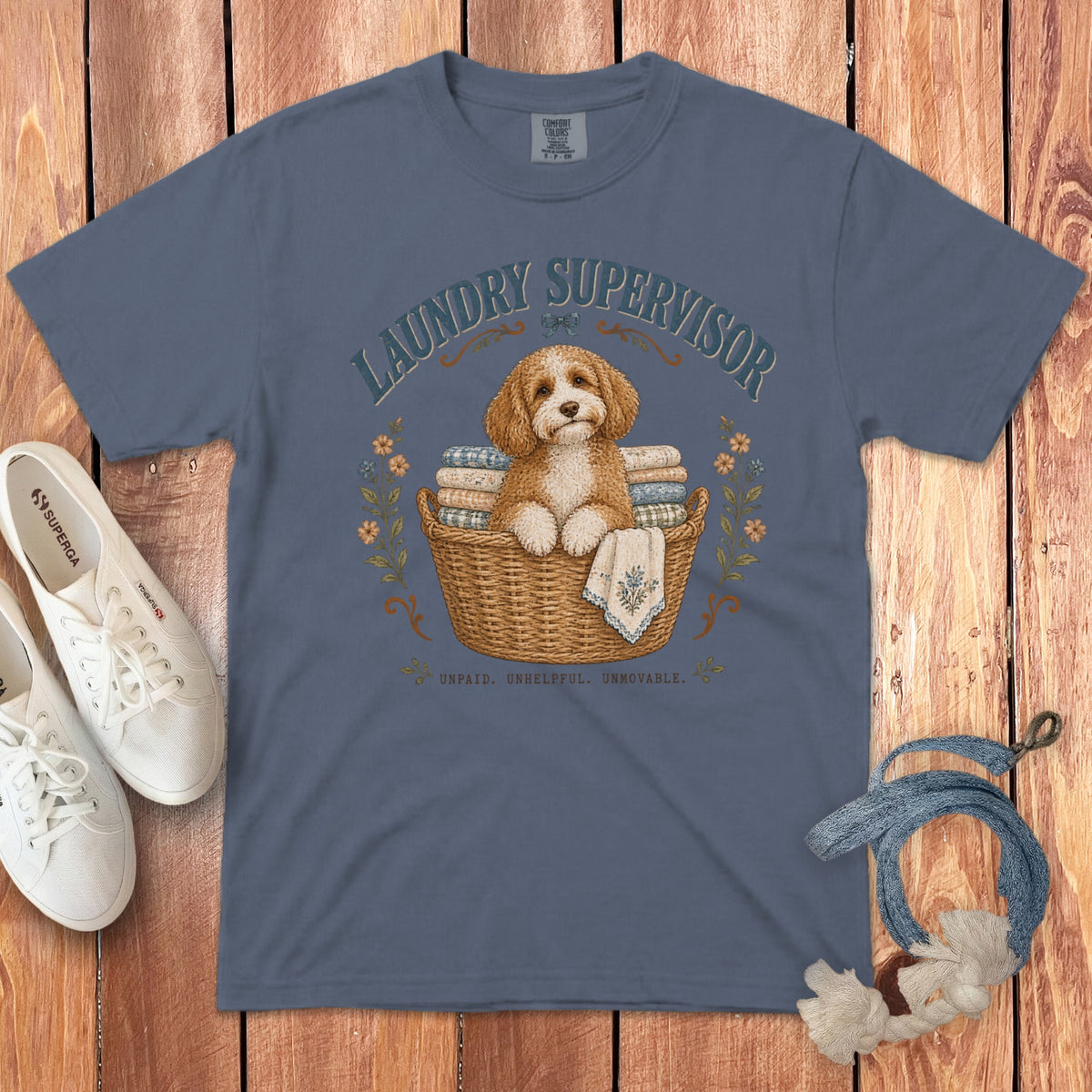 A blue crewneck t-shirt featuring a graphic of a fluffy dog in a laundry basket with text.