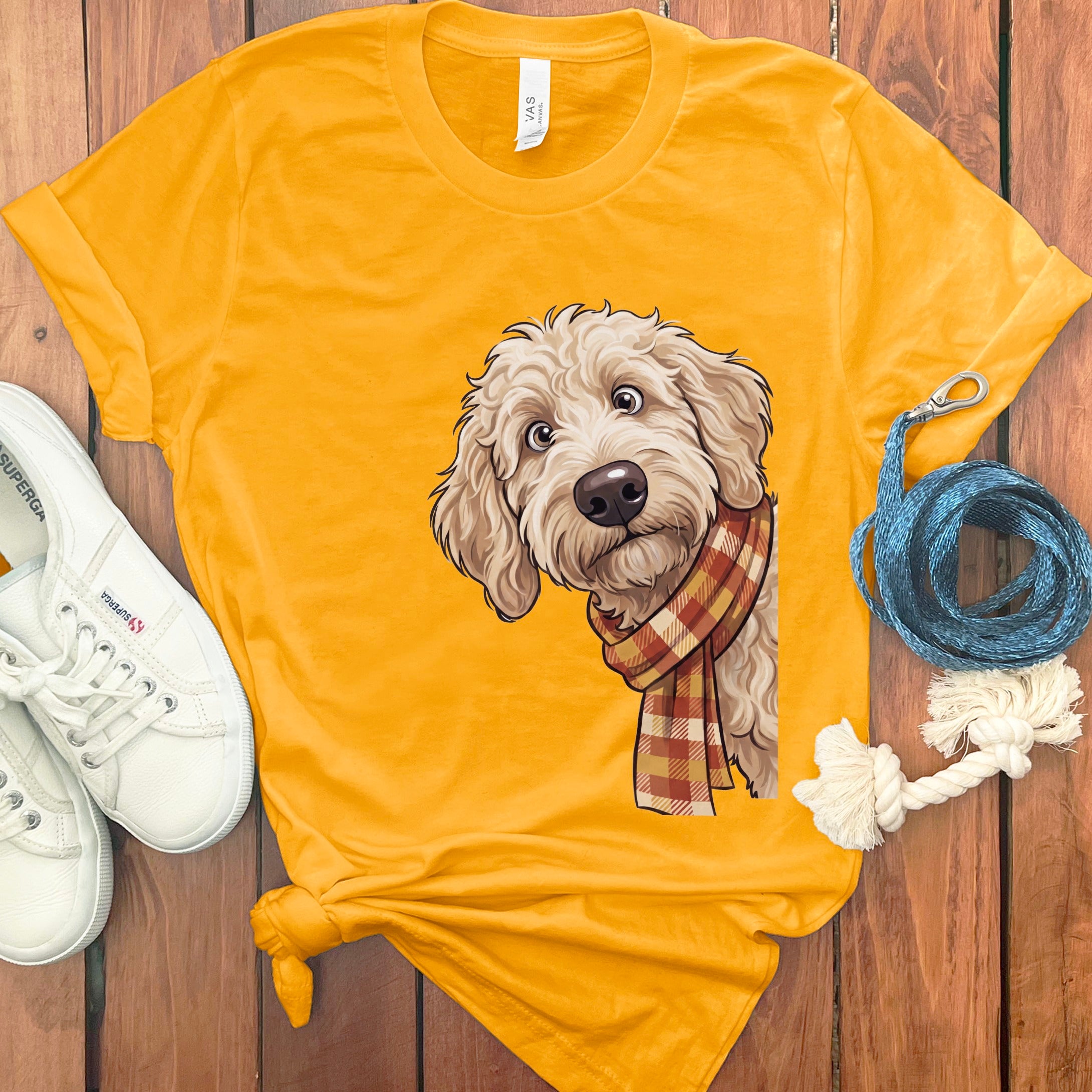 Gold t-shirt with a doodle dog wearing a plaid scarf illustration.