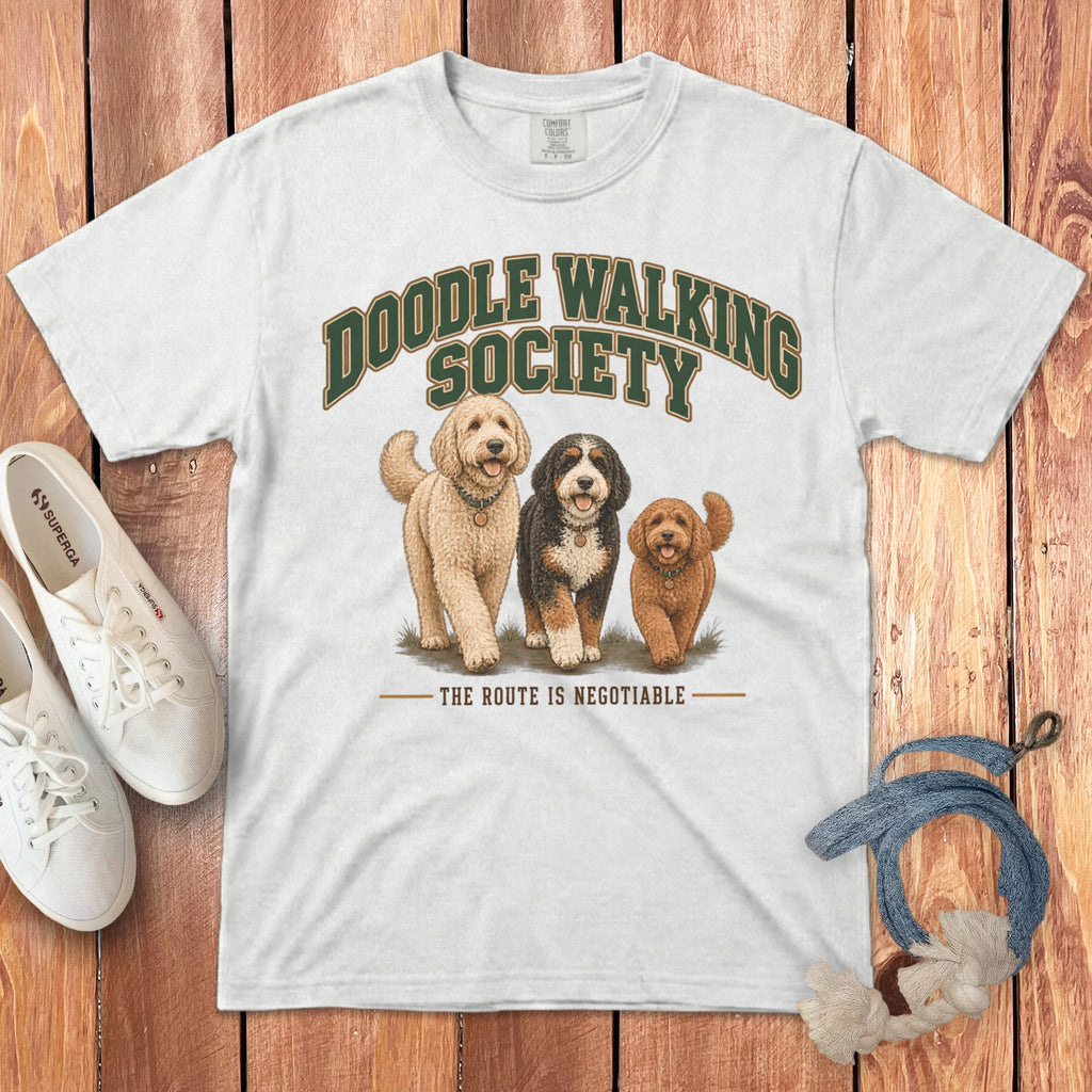 White t-shirt featuring three illustrated dogs and the text "DOODLE WALKING SOCIETY THE ROUTE IS NEGOTIABLE".