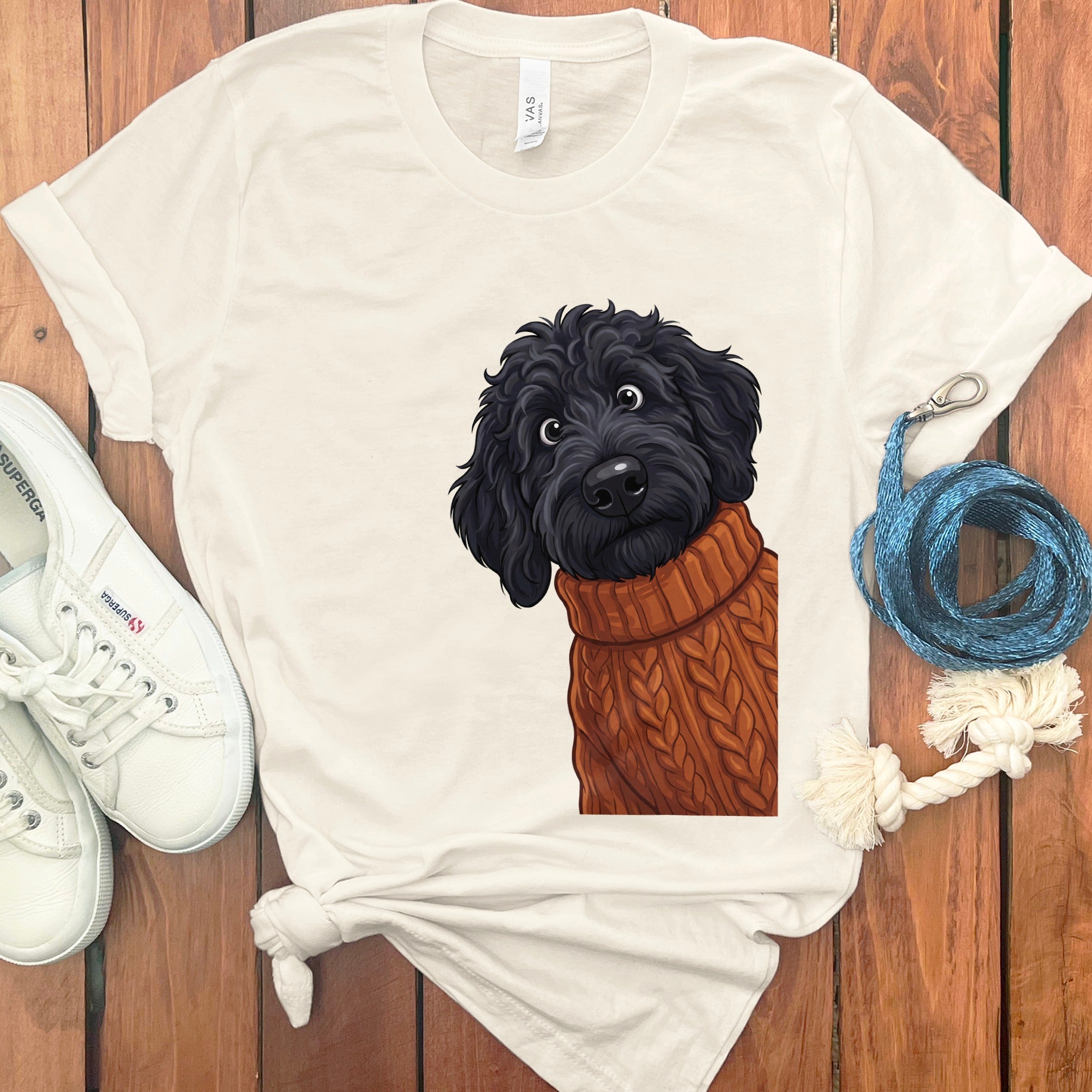 Cream t-shirt with illustration of a black dog wearing a cable knit sweater.