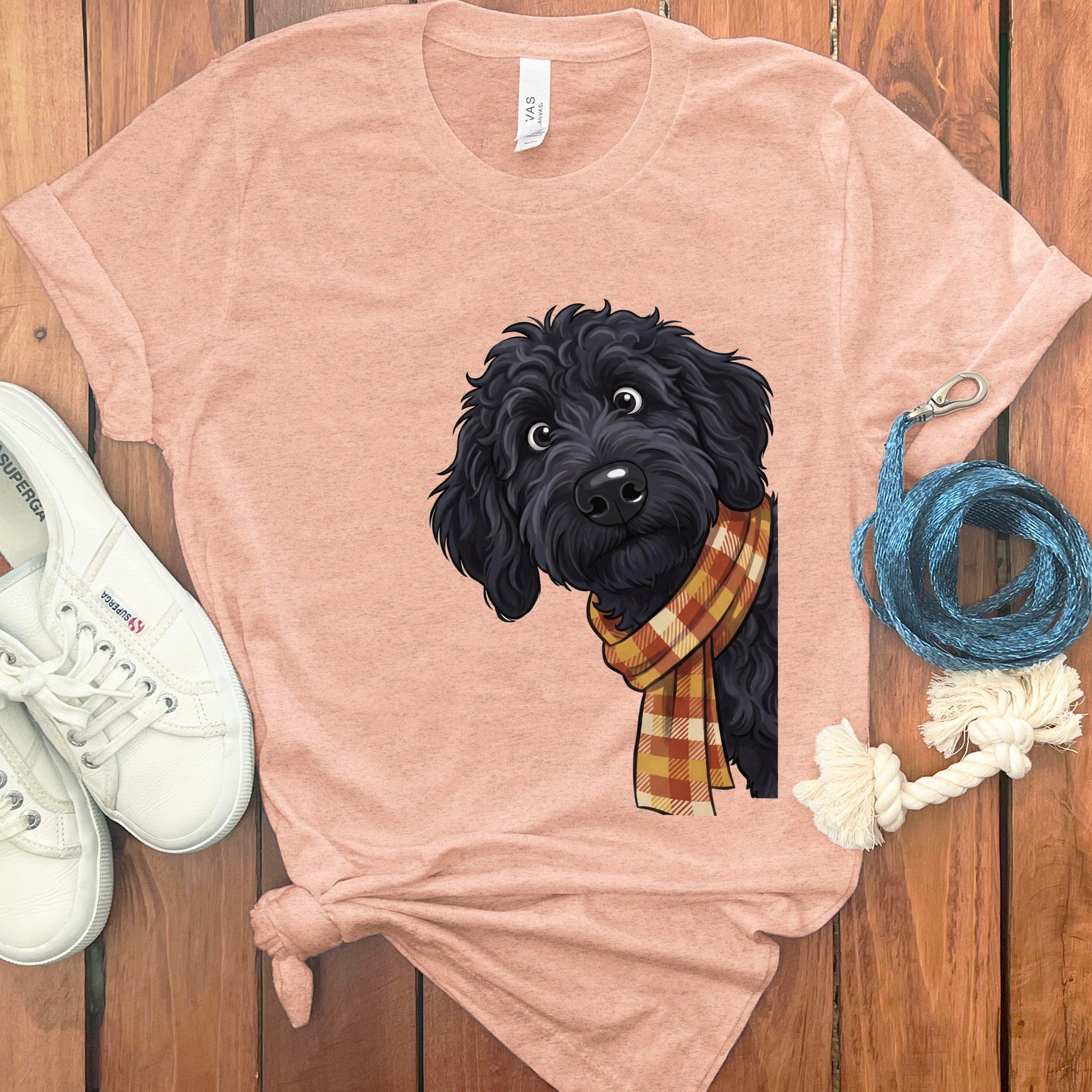 Pink t-shirt with black doodle dog wearing a plaid scarf graphic.