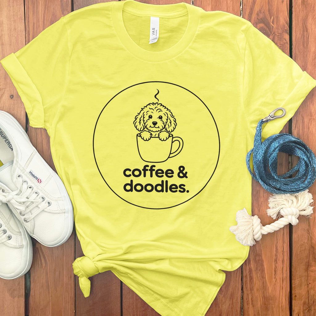 Yellow t-shirt with a black line drawing of a dog in a coffee cup and the text "coffee & doodles."