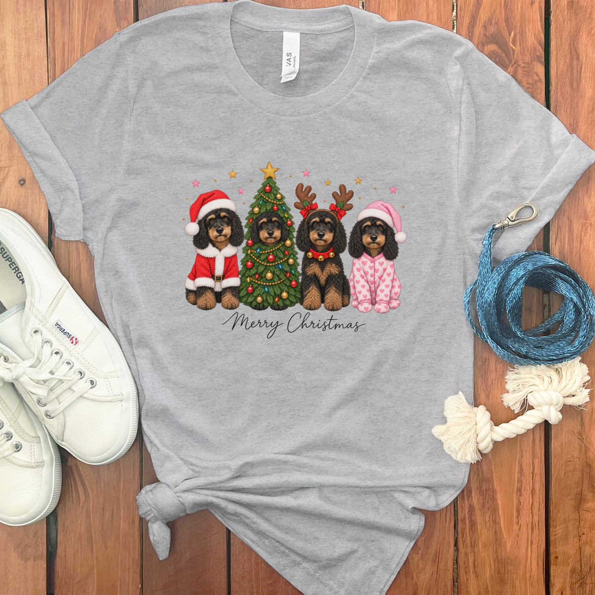 Heather gray t-shirt with a Merry Christmas graphic featuring four doodle dogs in holiday outfits and a decorated tree.