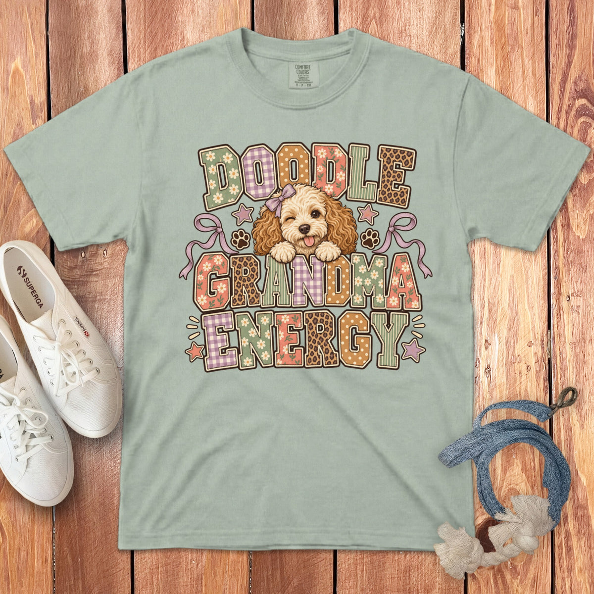 Sage green t-shirt with a Doodle Grandma Energy graphic featuring an illustrated dog on a wooden background.