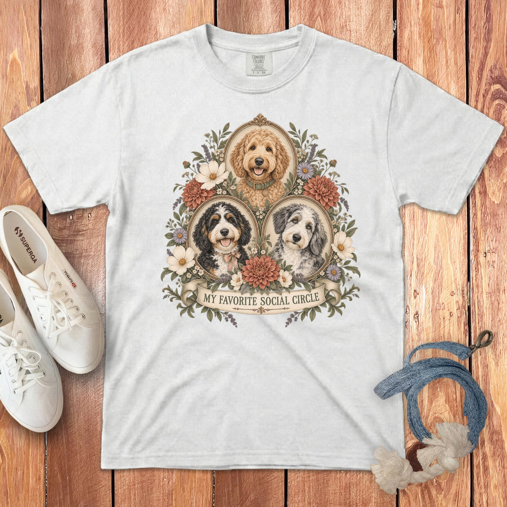 A white t-shirt featuring a graphic of three doodle dogs framed by flowers with the text "MY FAVORITE SOCIAL CIRCLE".