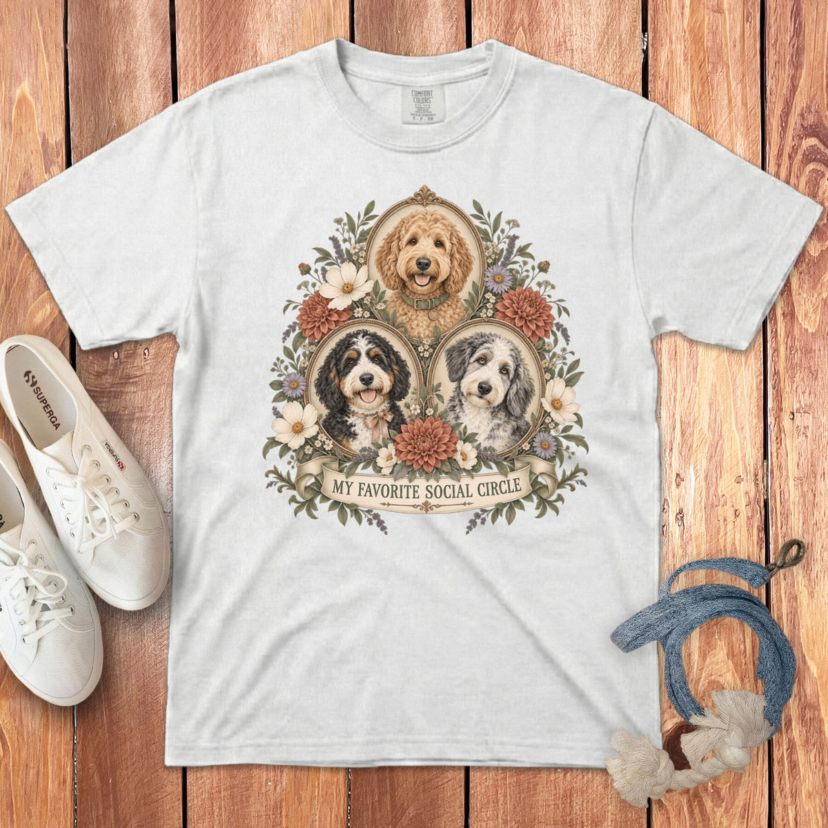 A white t-shirt featuring a graphic of three doodle dogs framed by flowers with the text "MY FAVORITE SOCIAL CIRCLE".