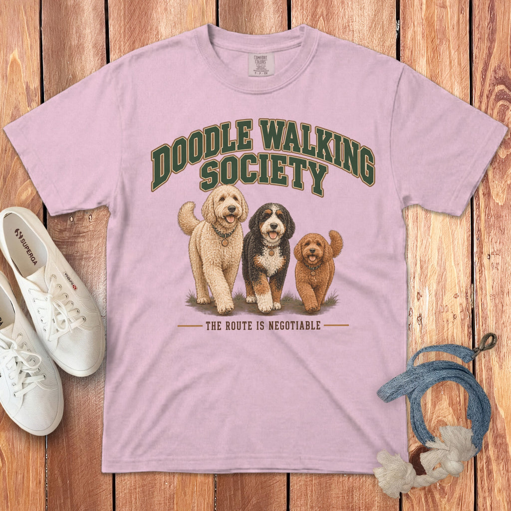A pink t-shirt featuring a graphic of three doodle dogs and text that reads Doodle Walking Society.