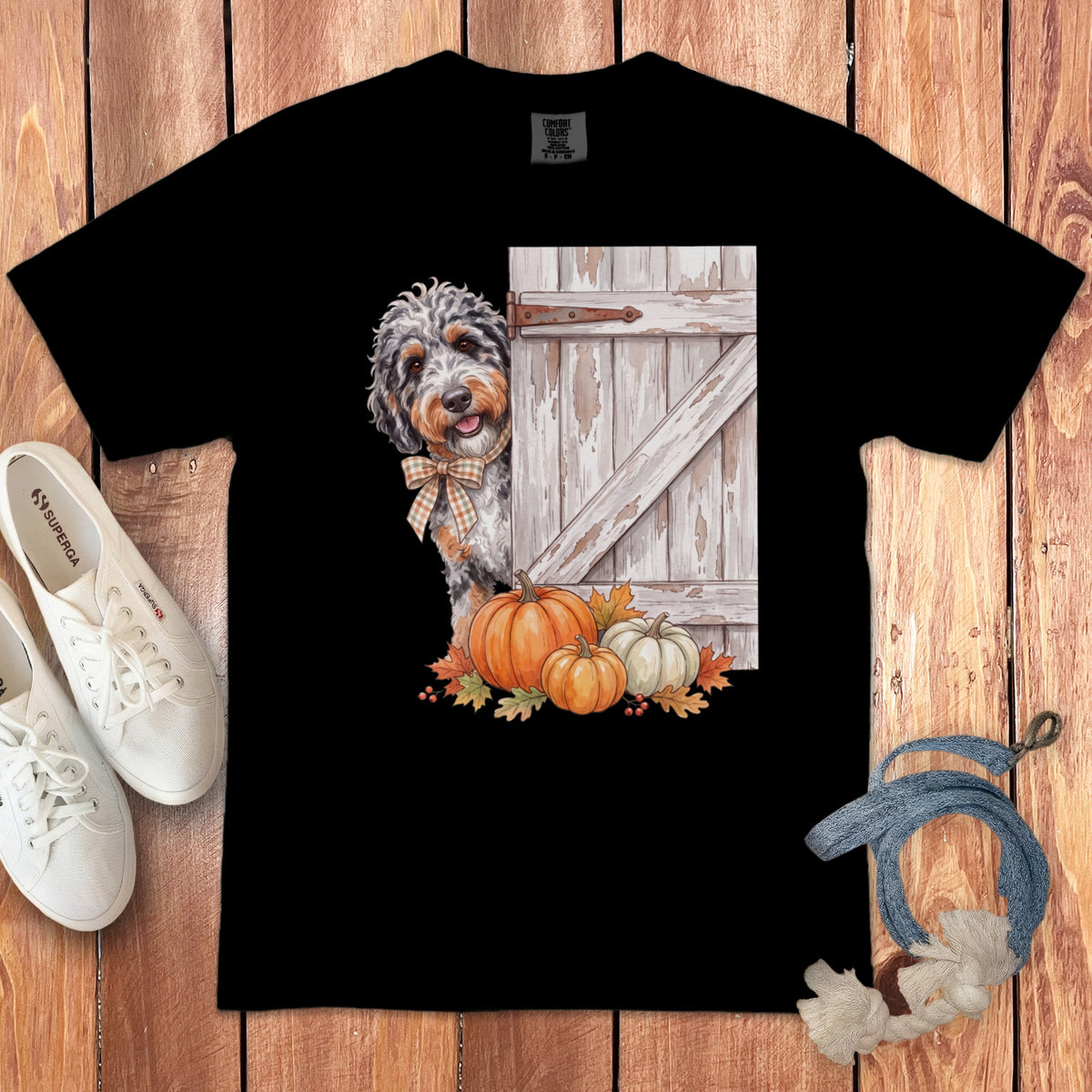 Black t-shirt featuring a dog peeking around a barn door with pumpkins and fall leaves.