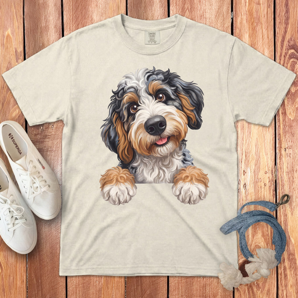 Cream t-shirt with a digital illustration of a Bernedoodle puppy peeking over the collar.