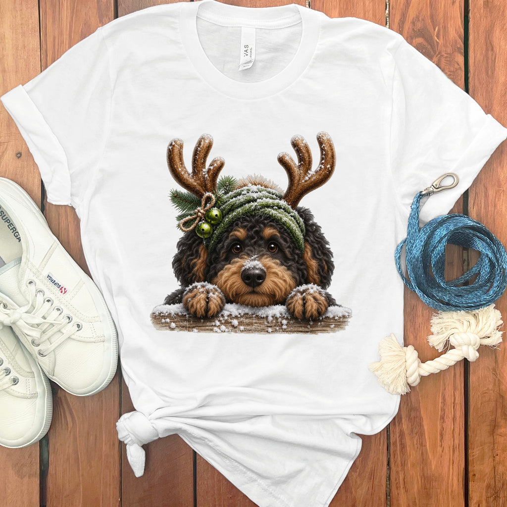 White t-shirt with a black and tan dog wearing reindeer antlers and a green beanie.