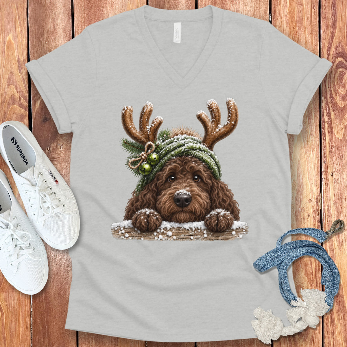 Brown dog wearing reindeer antlers and a green knit hat with bells on a t-shirt.