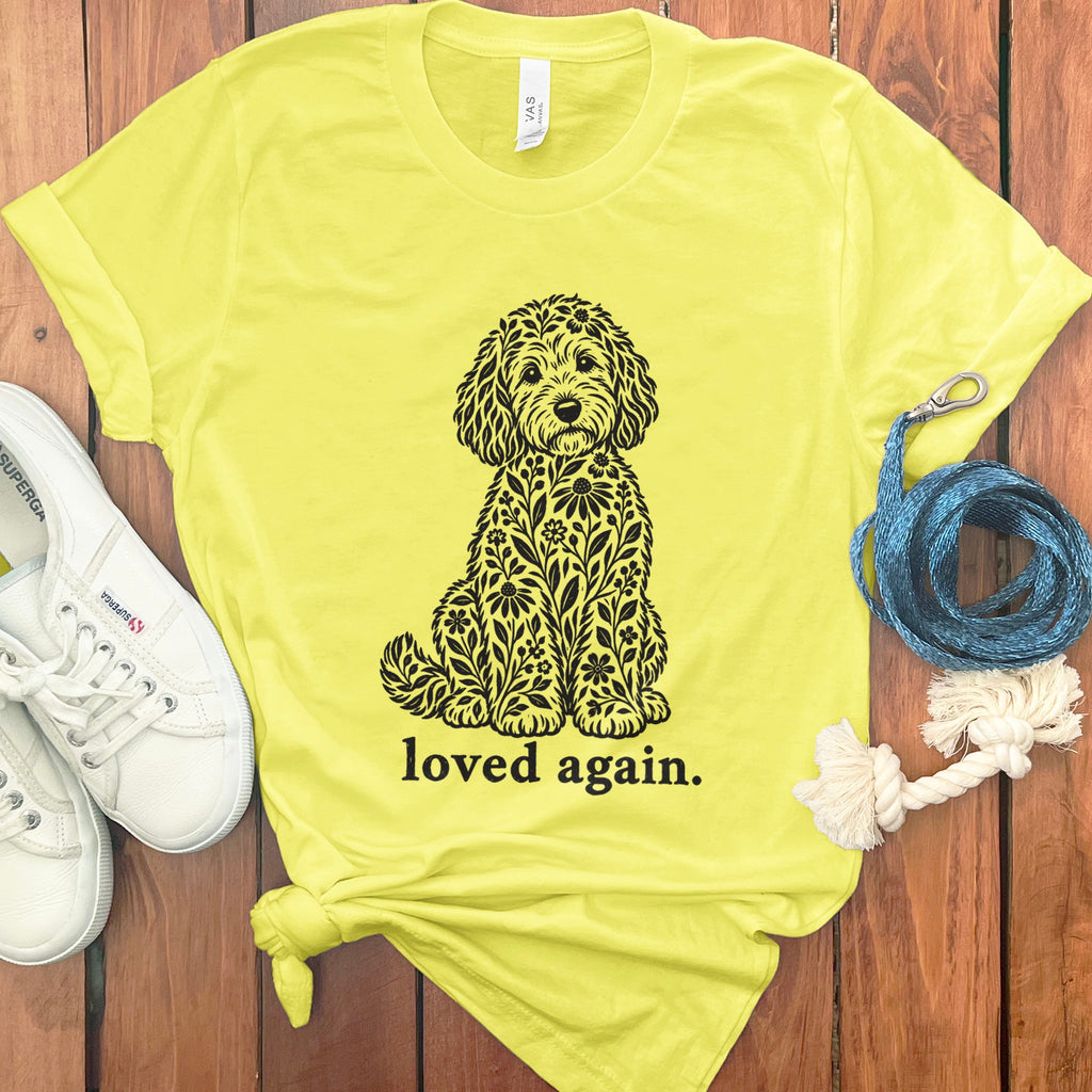 Yellow t-shirt with a black floral dog design and "loved again." text.
