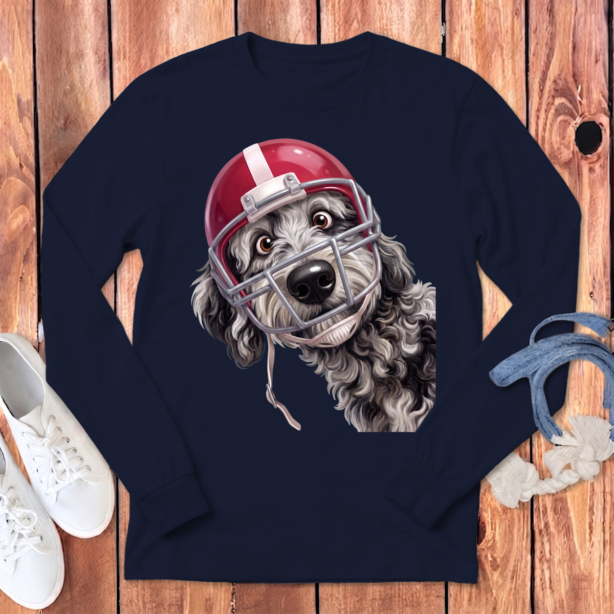 Fluffy dog wearing a red and silver football helmet, on a navy long-sleeve shirt.