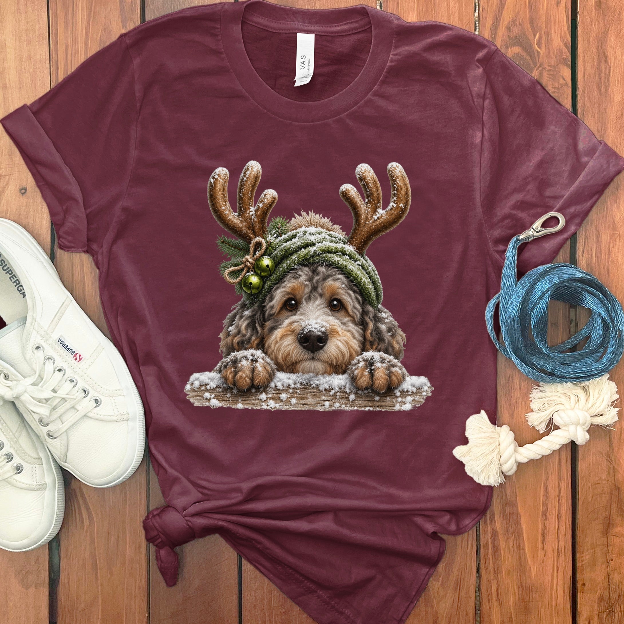 Maroon t-shirt featuring a fluffy dog with antlers and a snow-covered hat.