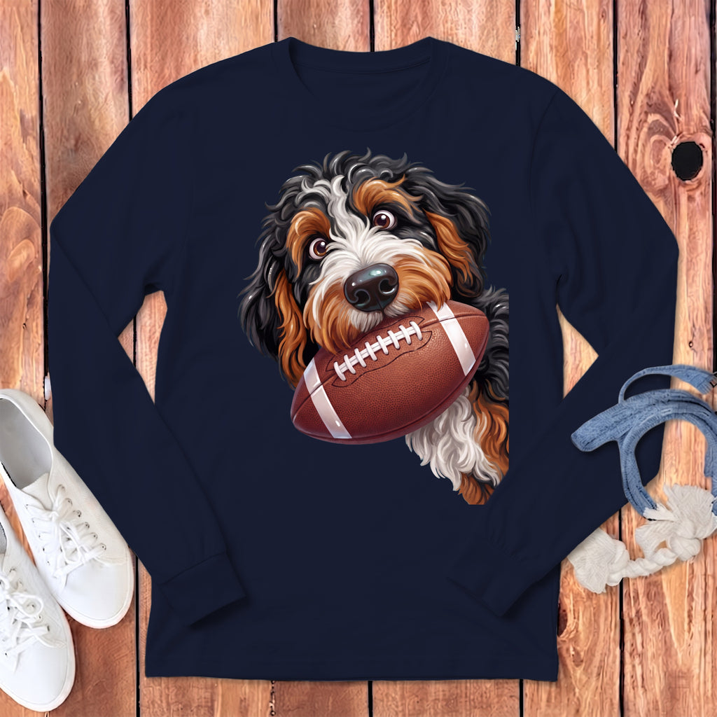 Bernese Mountain Dog with a football held in its mouth on a navy blue shirt.