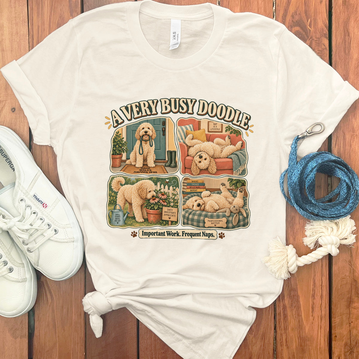 Cream t-shirt with a four-panel graphic of a doodle dog titled "A Very Busy Doodle".