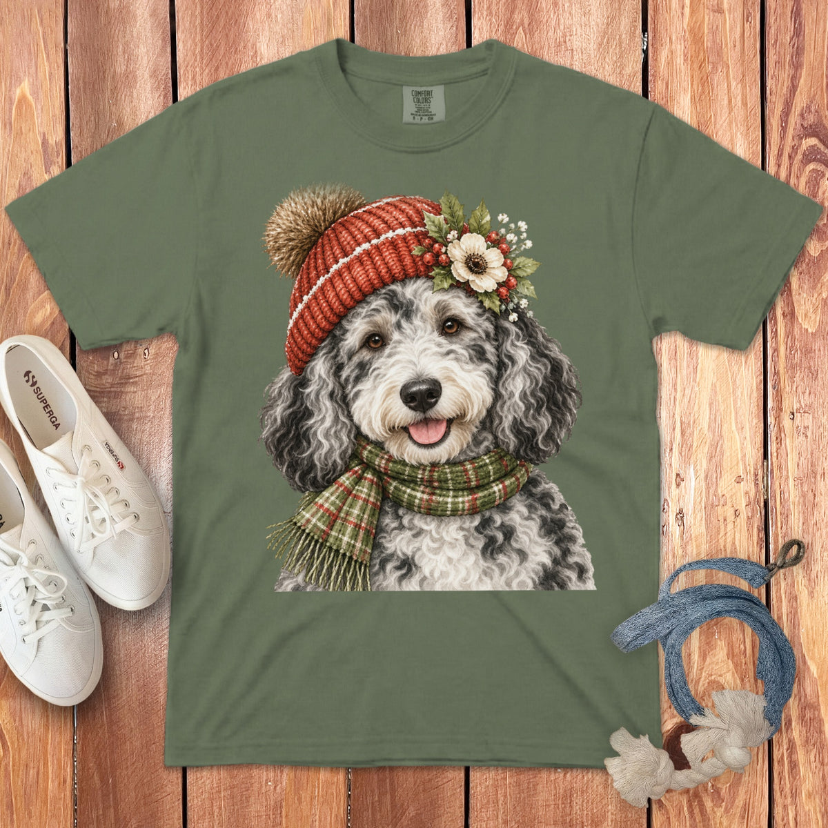 Green t-shirt with a watercolor illustration of a doodle dog wearing a red beanie and scarf.