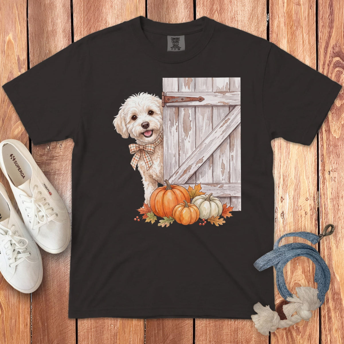 White dog with plaid bow peeking from behind a rustic door with pumpkins.