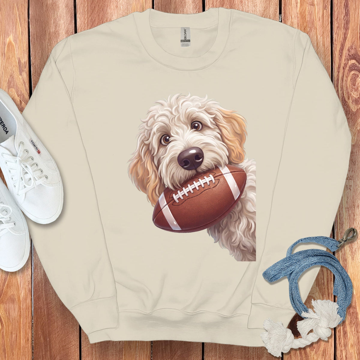 Cream sweatshirt with a goldendoodle holding a football design.