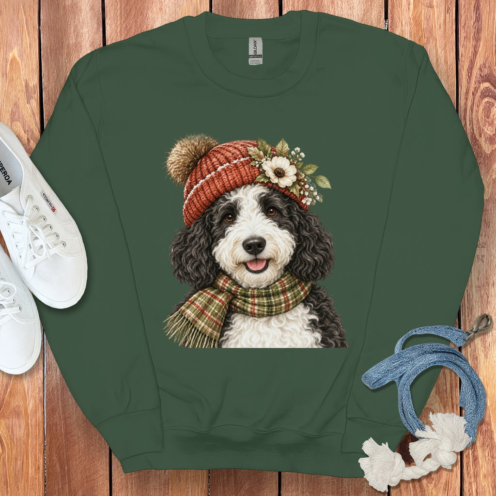 Bernedoodle dog wearing a red knit hat and plaid scarf, with flowers.
