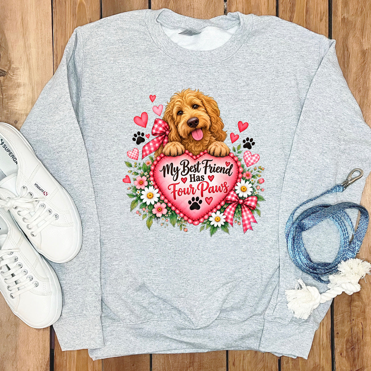 Light gray crewneck sweatshirt featuring a graphic of a golden puppy resting on a pink heart with the text "My Best Friend Has Four Paws".