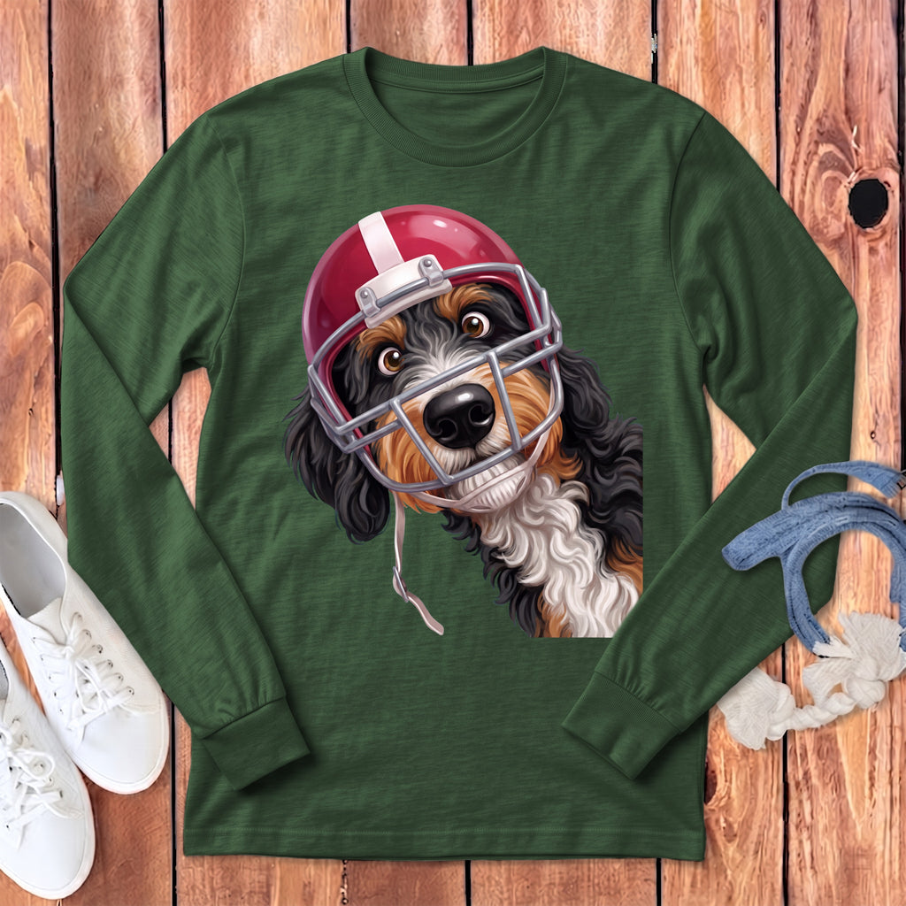 Bernese Mountain Dog wearing a red football helmet and facemask on a green long-sleeve shirt.