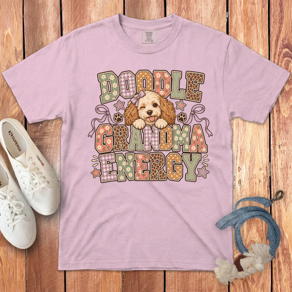 A light pink crewneck t-shirt featuring a doodle graphic and the text DOODLE GRANDMA ENERGY.