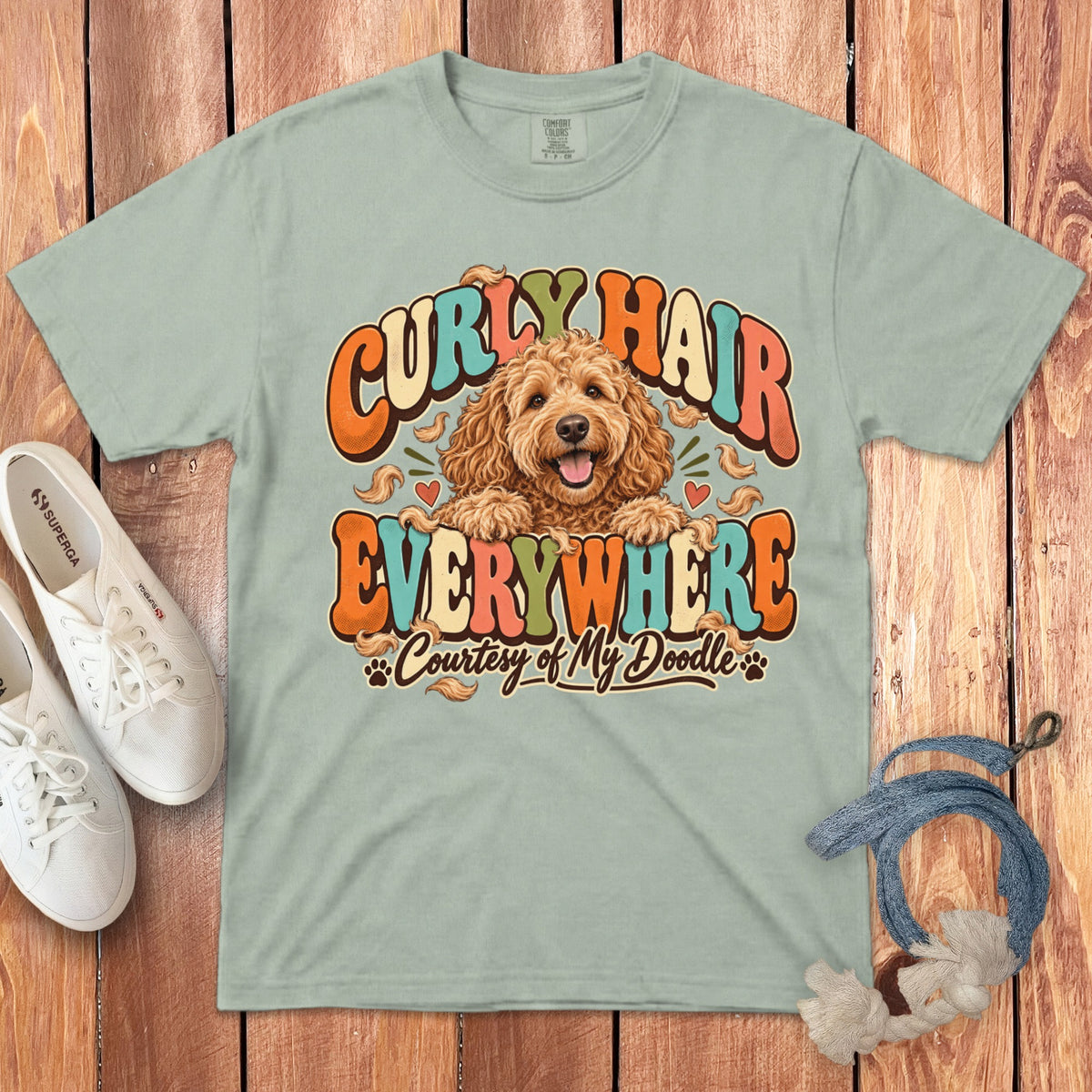 Light green t-shirt with doodle graphic saying "Curly Hair Everywhere Courtesy of My Doodle."