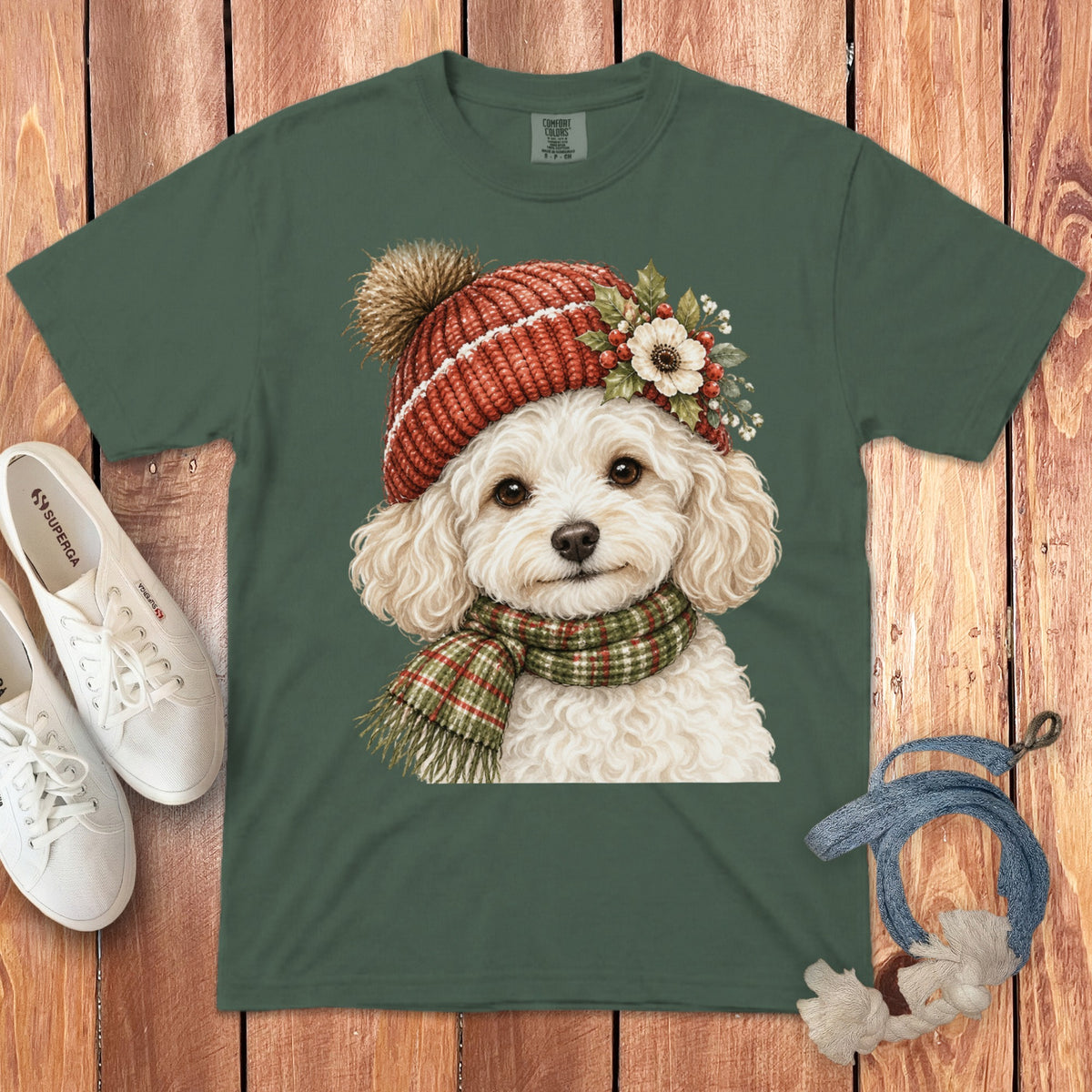 Green t-shirt featuring a white fluffy dog wearing a red knit hat and green plaid scarf.