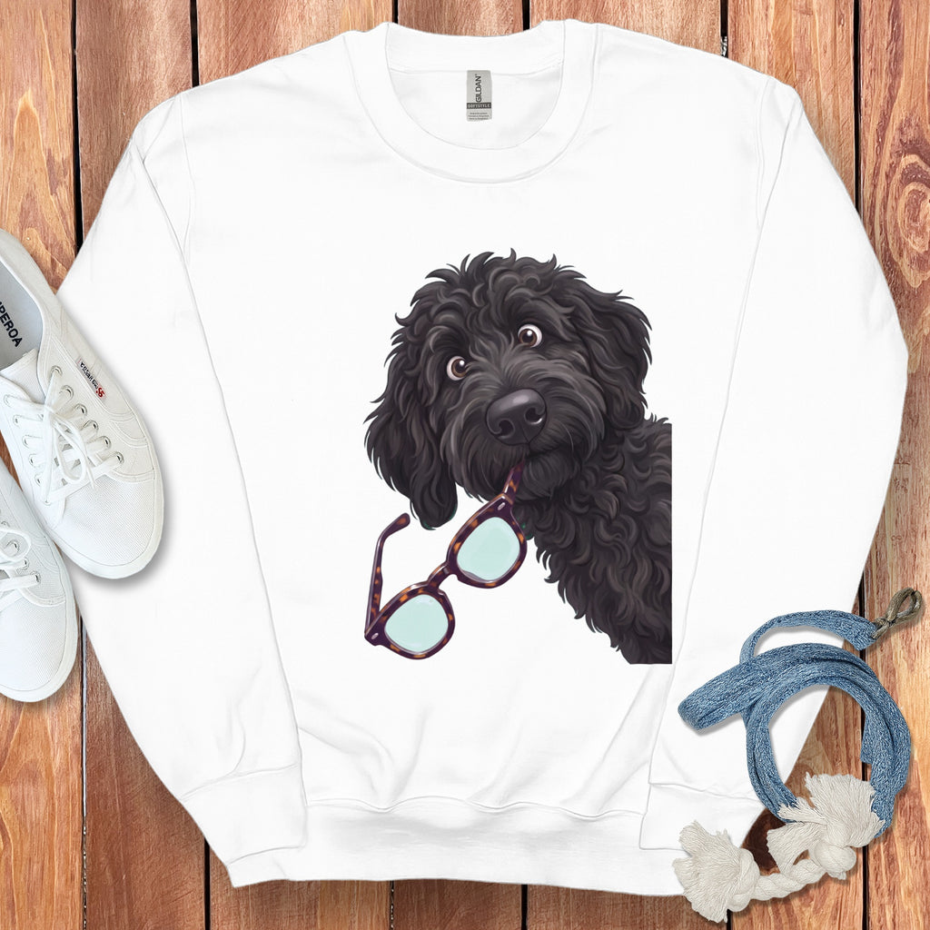 A white crewneck sweatshirt features an illustrated black doodle dog holding glasses in its mouth.