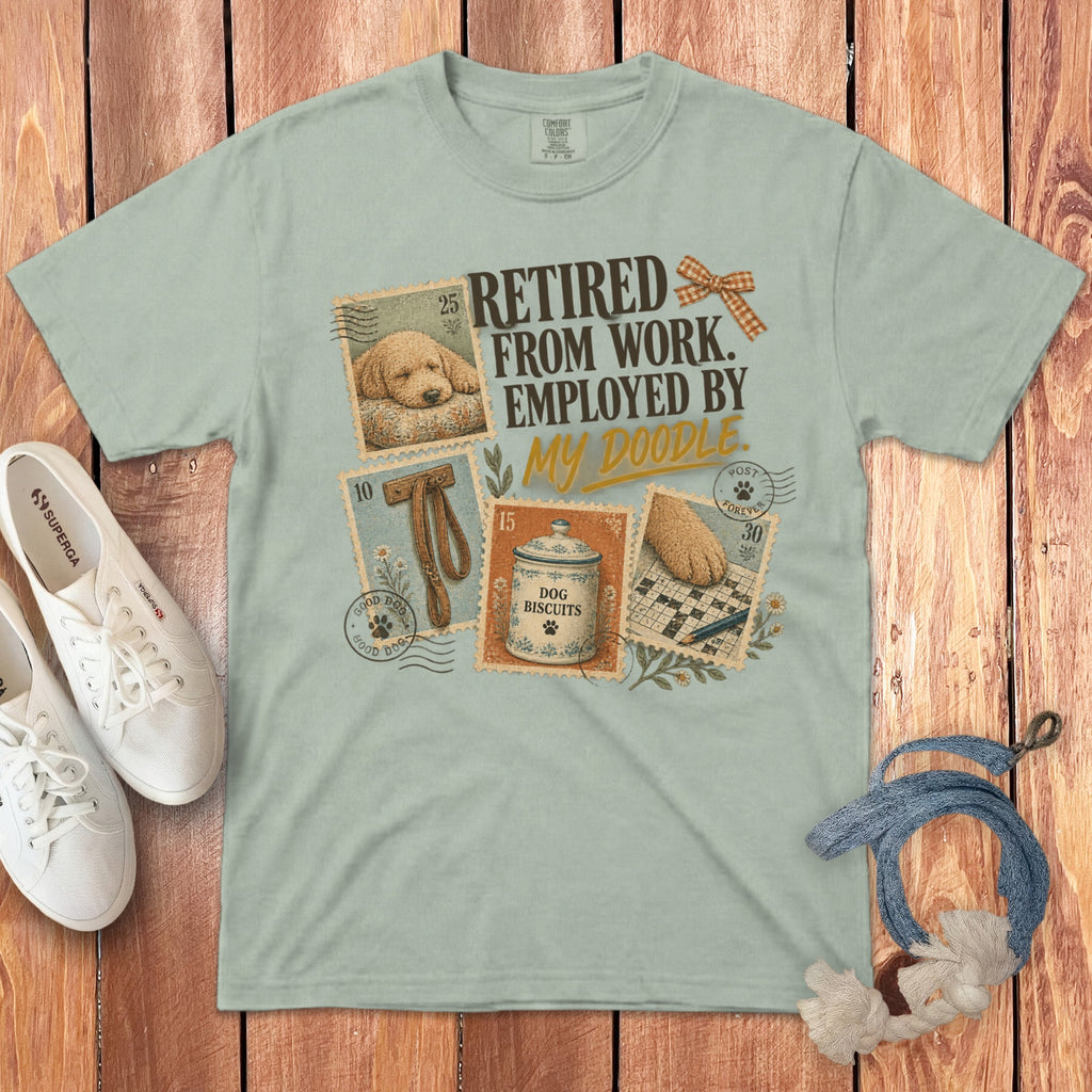 Sage green t-shirt featuring the text RETIRED FROM WORK EMPLOYED BY MY DOODLE alongside dog-themed graphics.