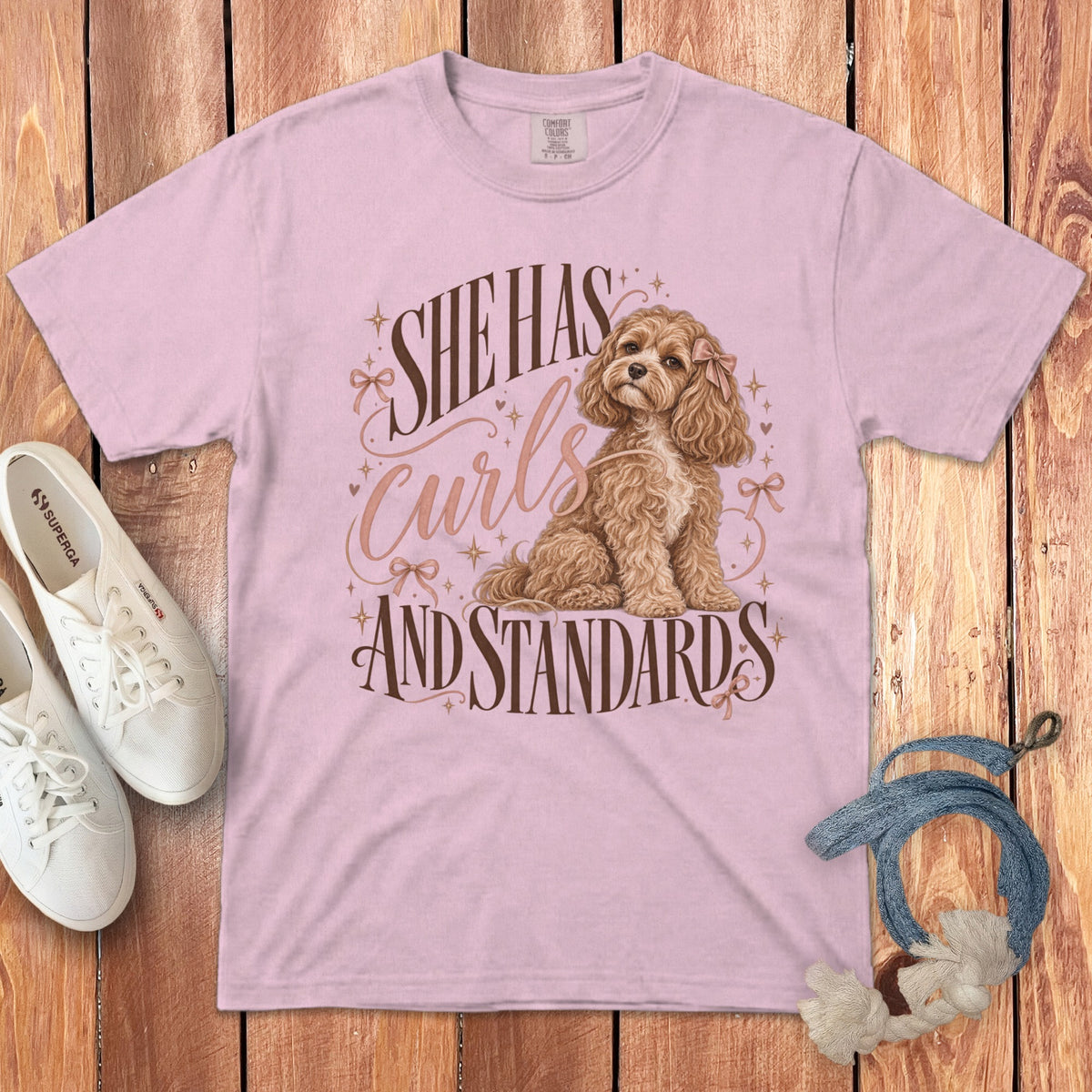 Light pink t-shirt with a curly brown dog graphic and text reading She Has Curls And Standards.