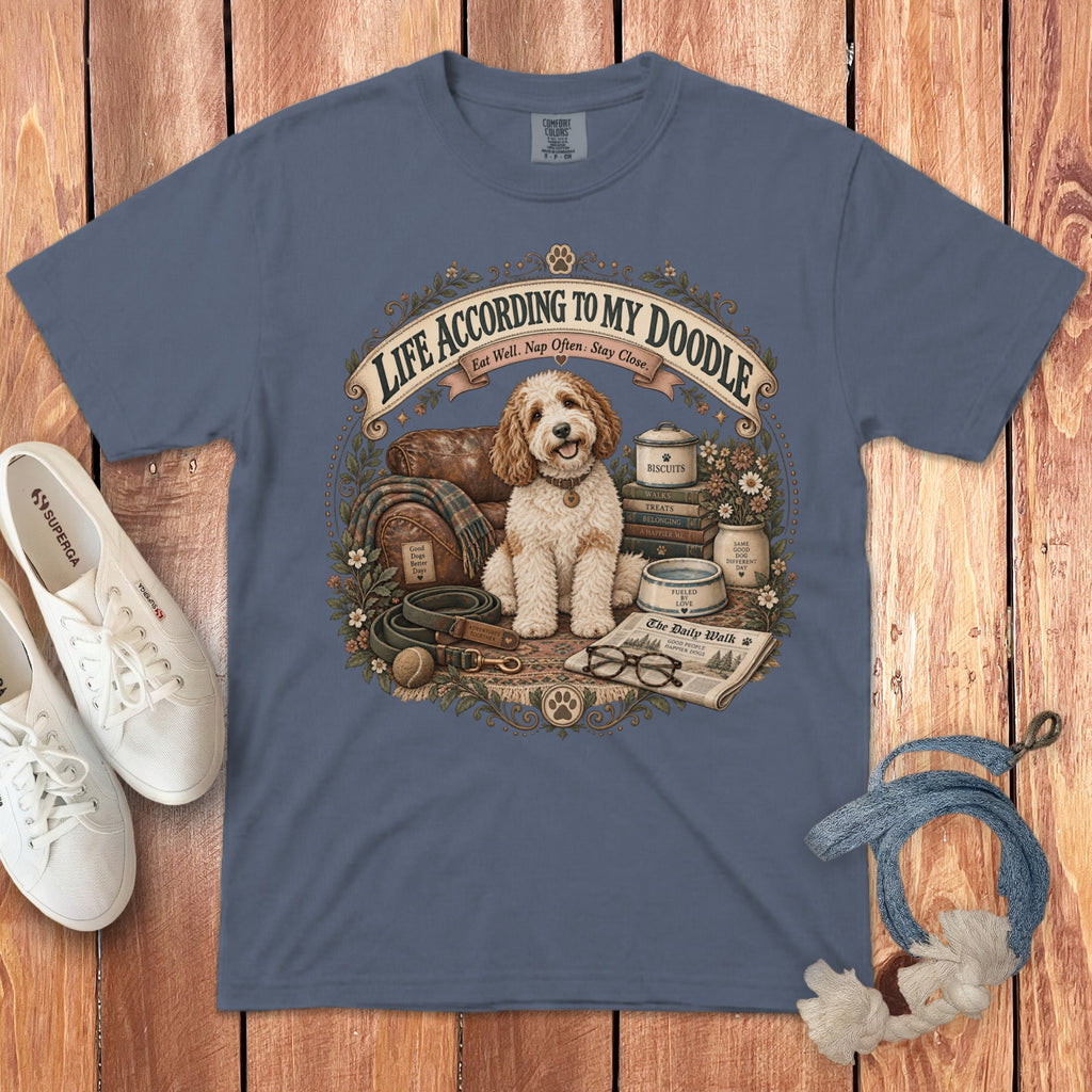 T-shirt with a doodle sitting by a leather chair, books, and dog accessories, text reads "LIFE ACCORDING TO MY DOODLE".