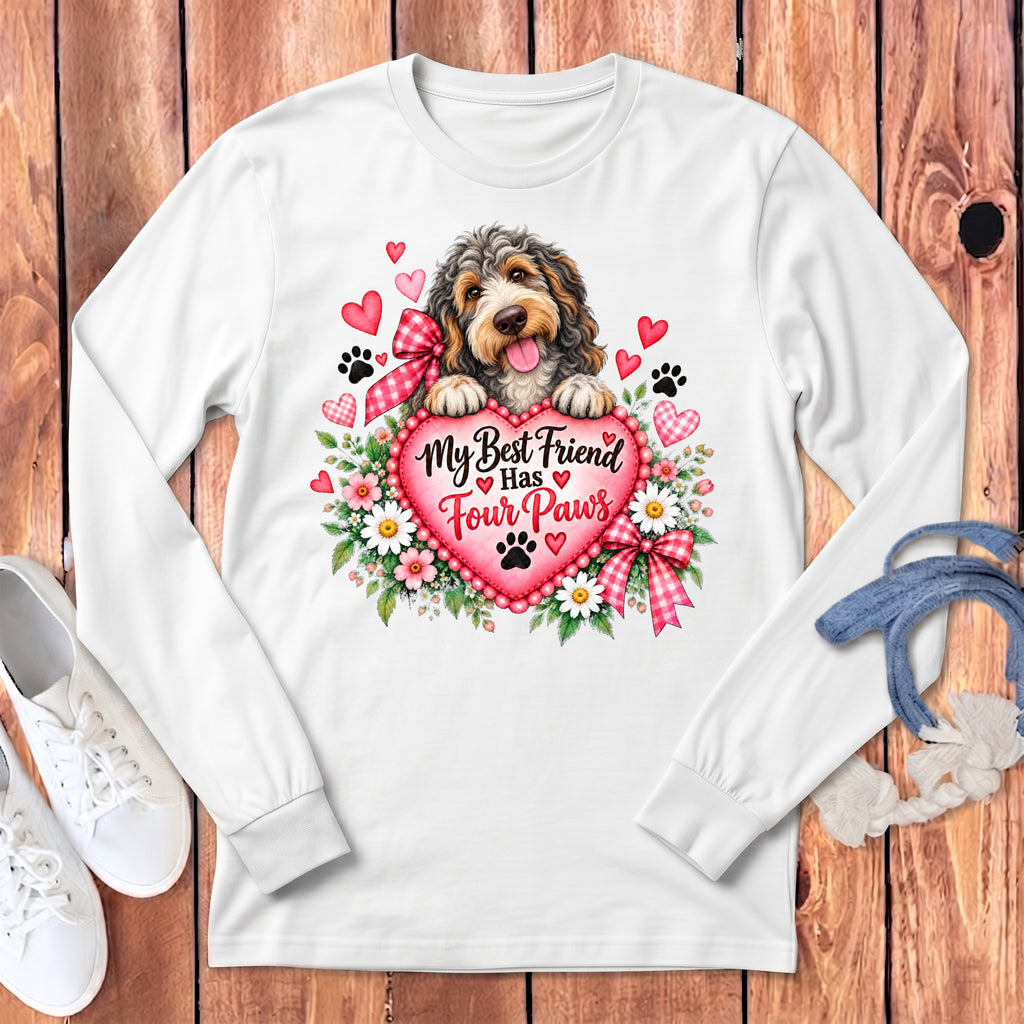 A white long-sleeved shirt features a graphic of a fluffy dog resting paws on a pink heart inscribed with My Best Friend Has Four Paws.